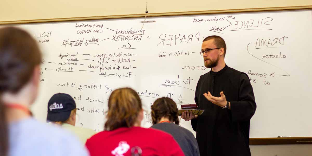 A monk speaks to students in a classroom